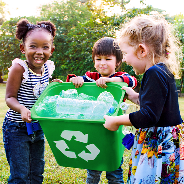Kids outside holding recycle bin of plastic bottles