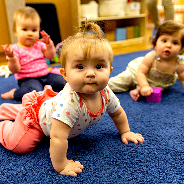 Three baby girls sitting on the carpet in the Infant classroom
