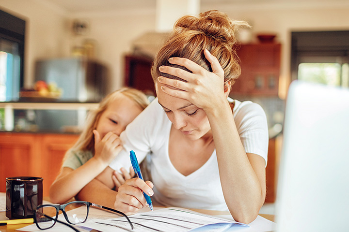 Mom working from home with daughter looking over her shoulder