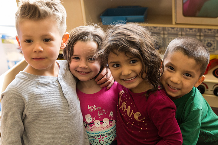 Four kids with their arms around each other smiling