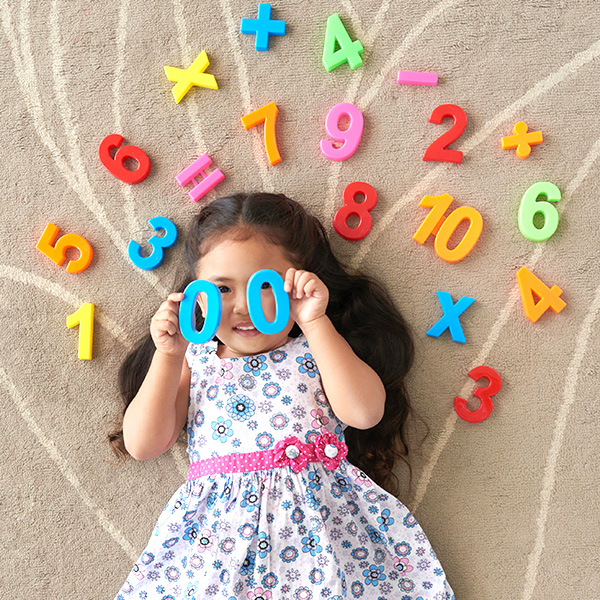 Little girl laying down surrounded by play numbers