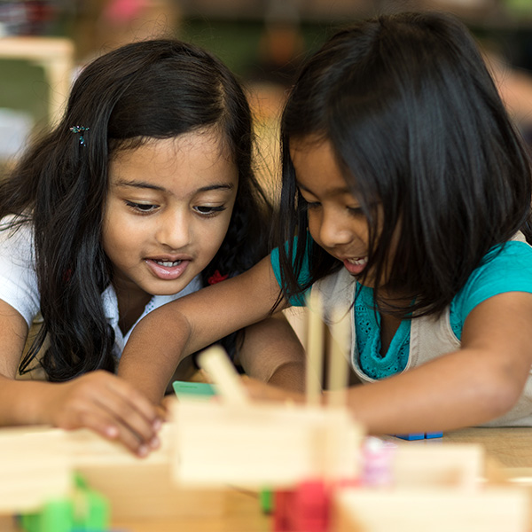 Two girls playing with blocks on a table