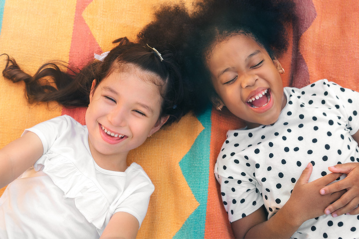 Two girls laughing laying on blanket