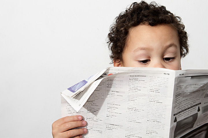 A young boy reading the newspaper