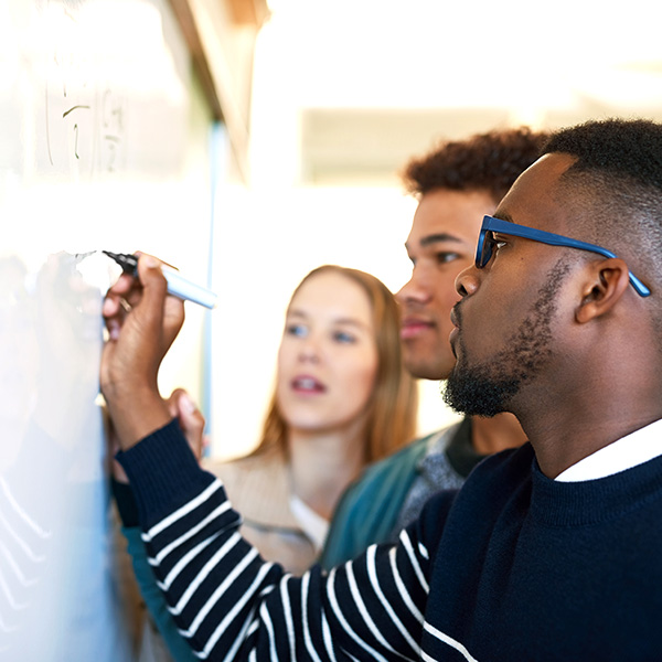 Three team members brainstorming at a whiteboard