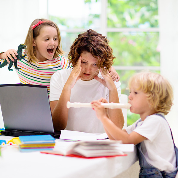 Mom trying to work at computer with her kids distracting her